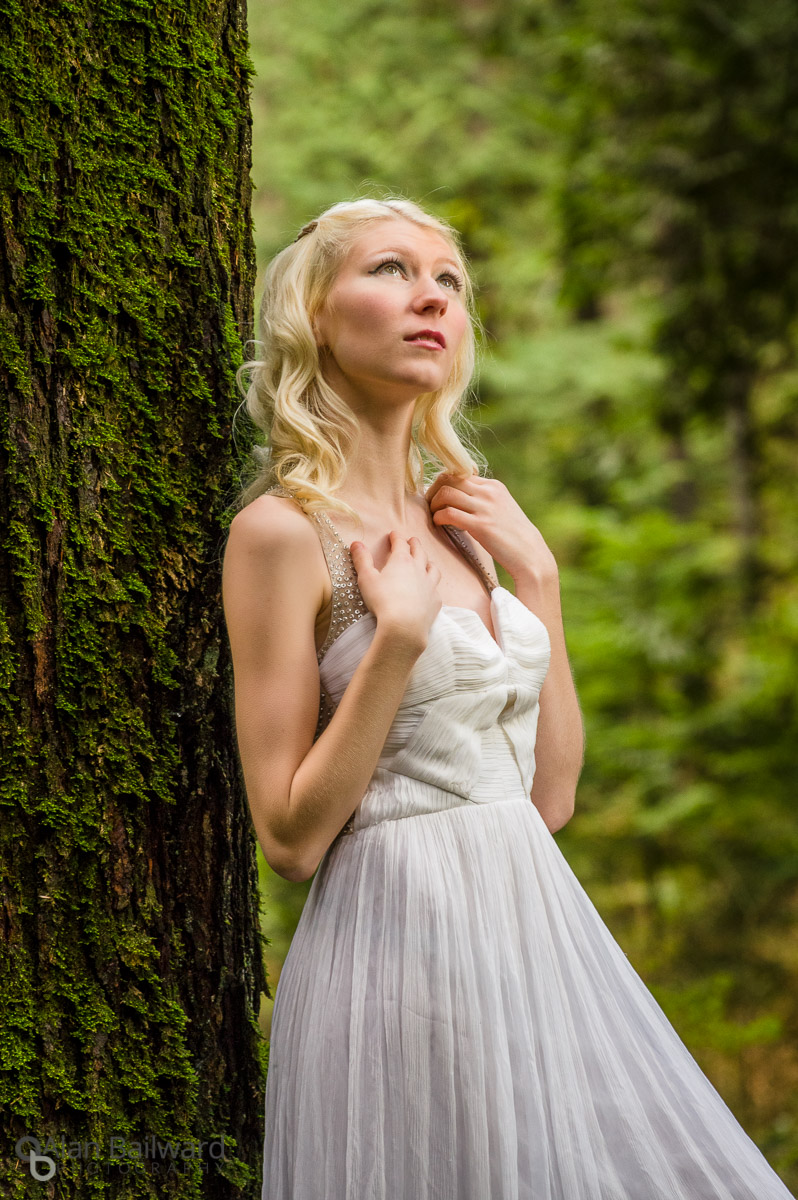 Model in white dress in front of cedar tree